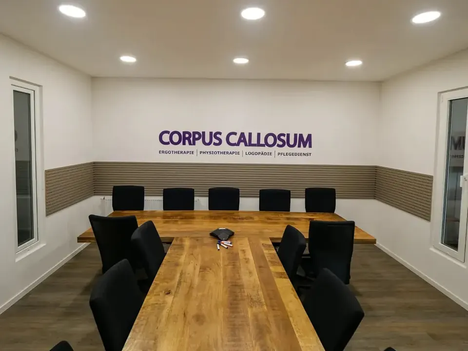 Besprechungsraum mit langem Holztisch und Corpus Callosum Schriftzug